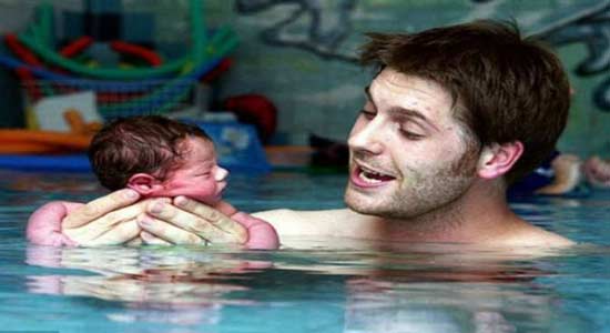 أب يعلم ابنه السباحة بعد يوم واحد من ولادته