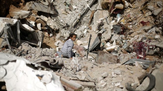 فتاة فلسطينية تجلس وسط حطام منزلها الذي دمر في العملية الإسرائيلية الموسعة على غزة الصيف الماضي.