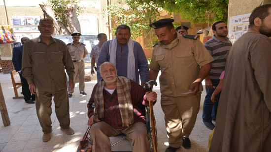  محافظ أسيوط يصطحب مسن إلى داخل اللجنة على كرسي متحرك للإدلاء بصوته في الاستفتاء