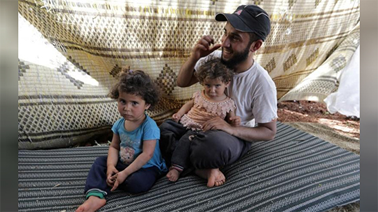 عائلة سورية تجتاز الأراضي الزراعية فرارا من هجمات إدلب