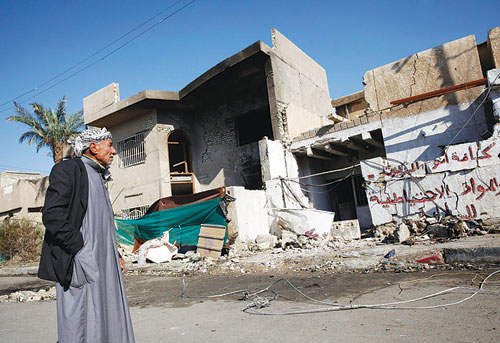 عراقي يمر أمس أمام مبنى تضرر جراء تفجير في حي الرسالة ببغداد أول من أمس (رويترز)