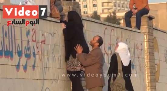 شباب يرفعون بنات وسيدات فوق سور جامعة الأزهر لمشاهدة المظاهرات