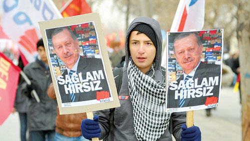 تركي يرفع صورتين لرئيس الوزراء التركي إردوغان أمس في مظاهرة احتجاجا على ملفات الفساد التي تشهدها الحكومة (رويترز)