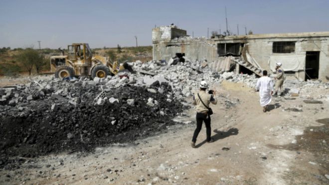  رجال الدفاع المدني السوري يتفقدون موقعا قيل إنه قصف في غارة روسية في ريف إدلب. 