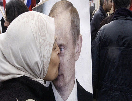 امرأة سورية تقبل صورة الرئيس الروسي بوتين