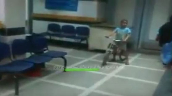 طفل يلهو بدراجة بين غرف الكشف بمستشفي المبرة بالمنيا