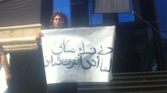 سيدة ترفع لافتة  على سلم الصحفيين بعنوان 