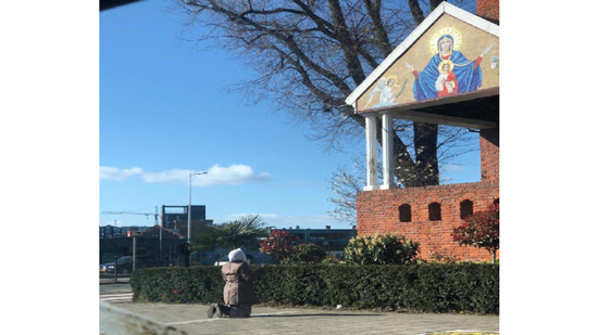 سيدة تصلي أمام باب كنيسة السيدة العذراء مريم بأمستردام-هولندا 