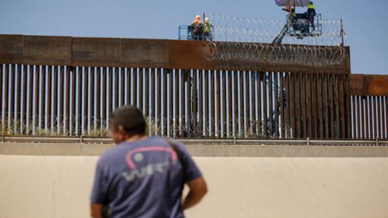 عمال أمريكيون يضعون أسلاكا شائكة على سياج حدودي على الحدود الأمريكية مع المكسيك